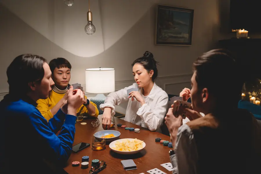 Unos amigos juegan a las cartas alrededor de una mesa.